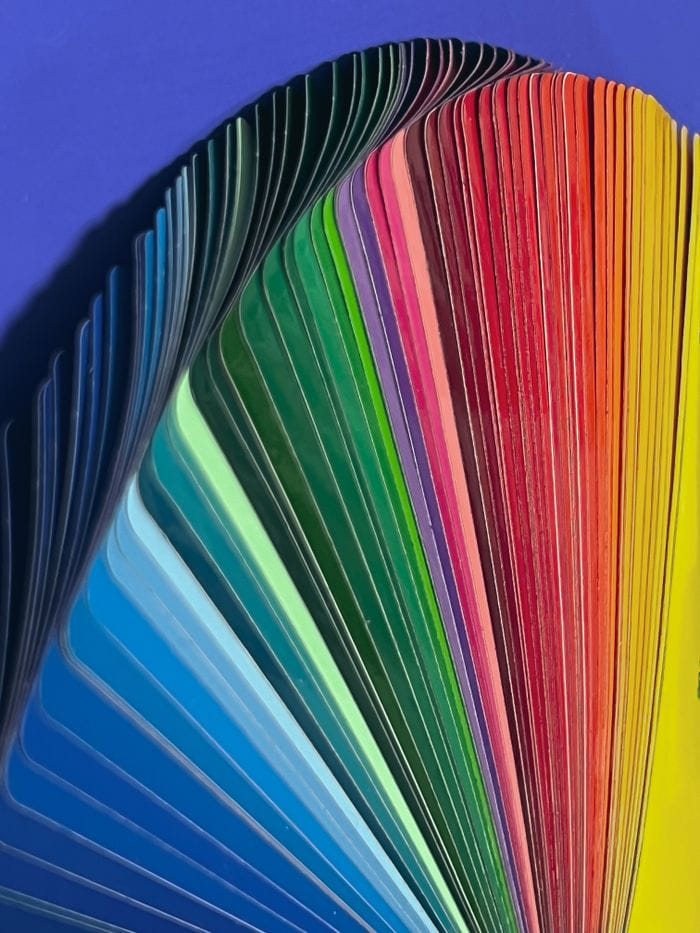 A colorful fan of vibrant color samples in a rainbow spectrum on a blue background.