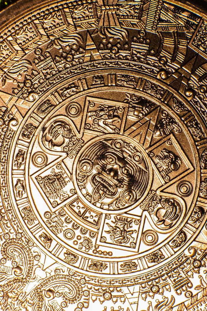 Close-up of a detailed Aztec calendar carved in copper, showcasing intricate designs and cultural significance.