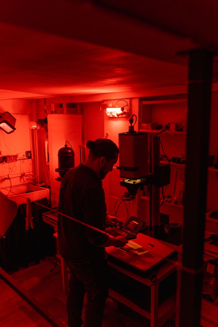 Photographer developing film negatives in a dimly lit darkroom, creating a nostalgic atmosphere.