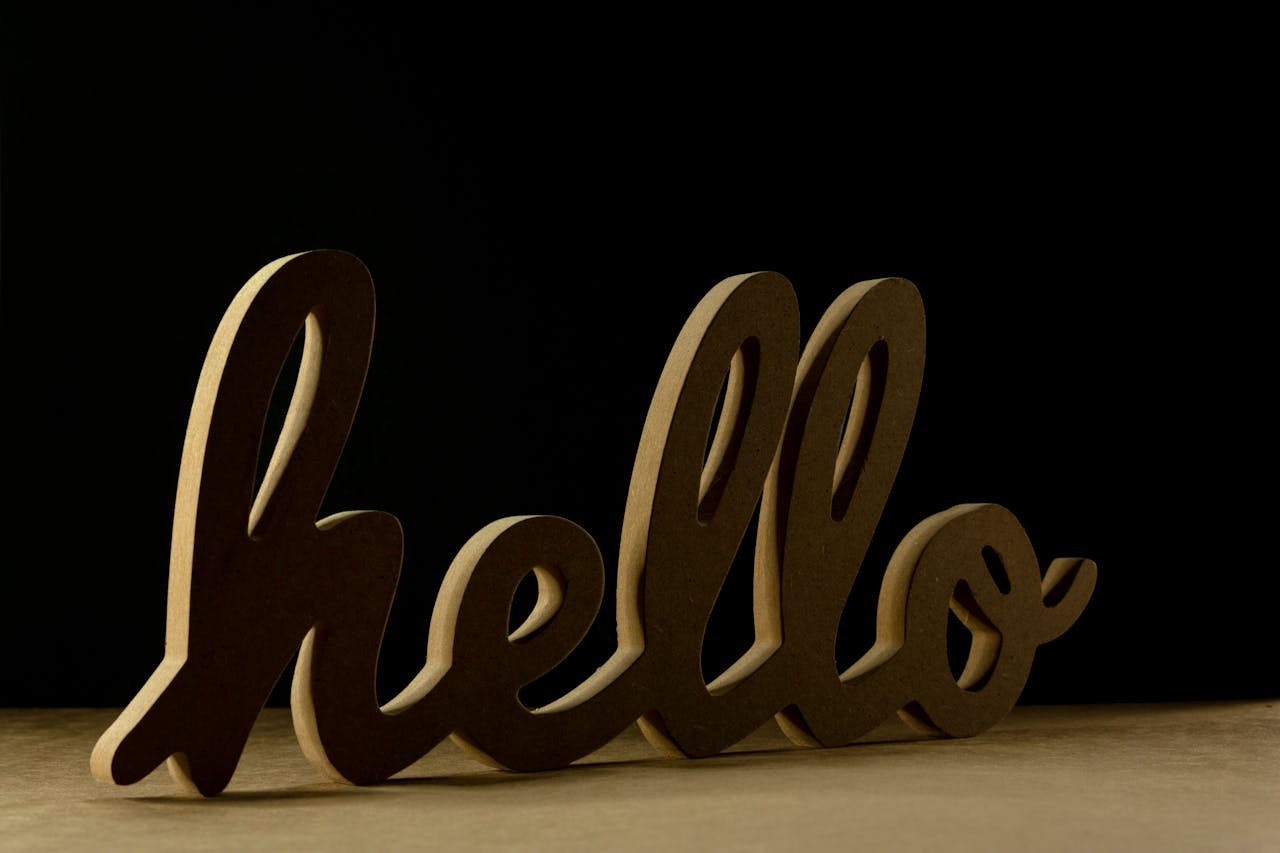 Elegant wooden 'hello' sign on a dark background, perfect for modern decor and design themes.